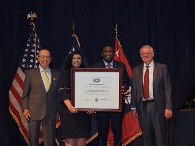 Mayor Dale V.C. Holness and Paola Isaac Baraya Receive President's "E" Award for Export Service from Secretary of Commerce Wilbur Rosson.