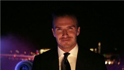 David Beckham ferries the Olympic torch along the Thames via speedboat.